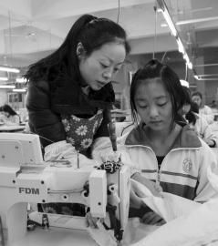 大英縣中等職業技術學校內，企業服裝技師正指導學生進行縫紉操作。